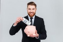 Business man putting money in piggy bank