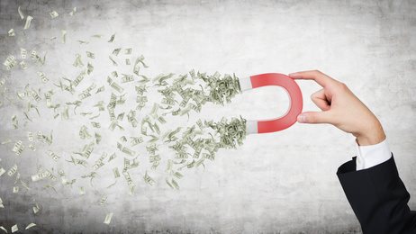 hand attracts money with a large red magnet